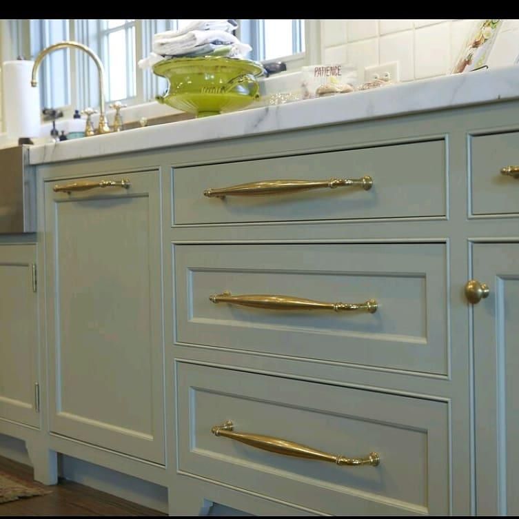 Brass appliance pulls on green cabinets
