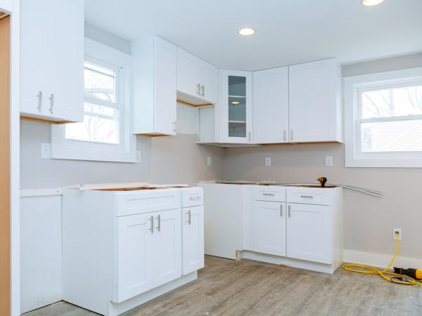 New white kitchen cabinets with a bare wall above the counter